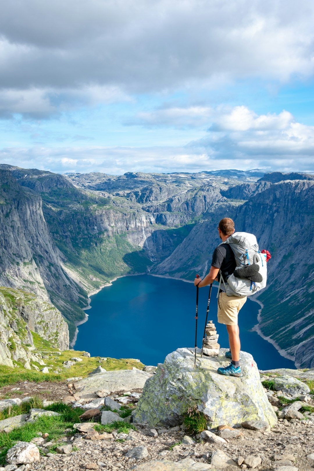 man-standing-on-rock-looking-towards-lake-bklhxgbyfdi man-standing-on-rock-looking-towards-lake-bklhxgbyfdi